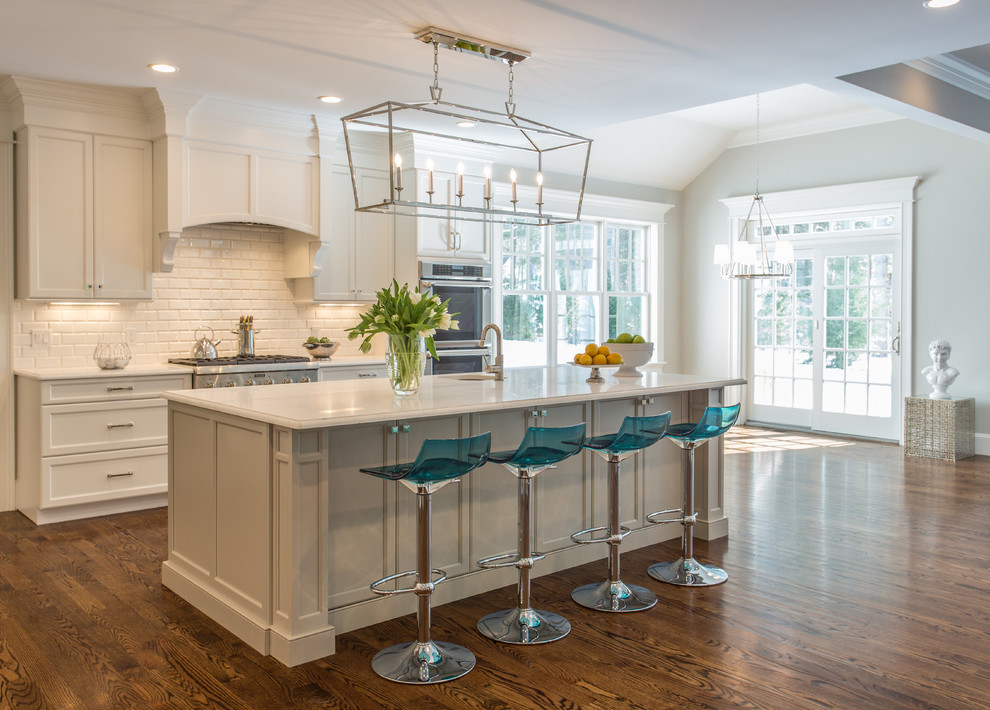Mid-sized transitional galley open plan kitchen in Boston with an undermount sink, recessed-panel cabinets, white cabinets, white splashback, subway tile splashback, stainless steel appliances, dark hardwood floors and with island.