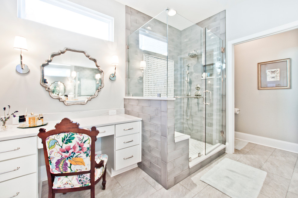 Photo of a transitional bathroom in Nashville with flat-panel cabinets, white cabinets, a corner shower, gray tile, subway tile, beige walls and a hinged shower door.
