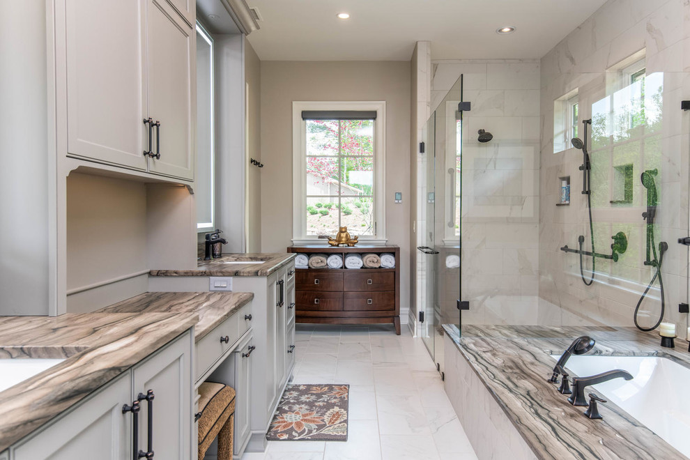 This is an example of a large transitional master bathroom in Other with recessed-panel cabinets, beige cabinets, an undermount tub, a corner shower, white tile, marble, beige walls, marble floors, an undermount sink, quartzite benchtops, white floor, a hinged shower door and beige benchtops.