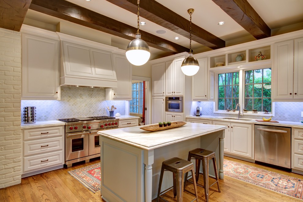 Photo of a traditional l-shaped kitchen in Austin with an undermount sink, raised-panel cabinets, stainless steel appliances, medium hardwood floors and with island.