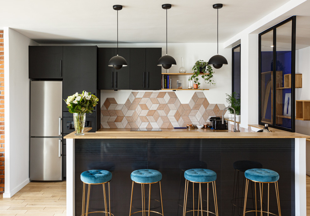 Design ideas for a mid-sized contemporary galley open plan kitchen in Paris with a single-bowl sink, flat-panel cabinets, black cabinets, wood benchtops, orange splashback, ceramic splashback, black appliances, light hardwood floors, with island, beige floor and beige benchtop.