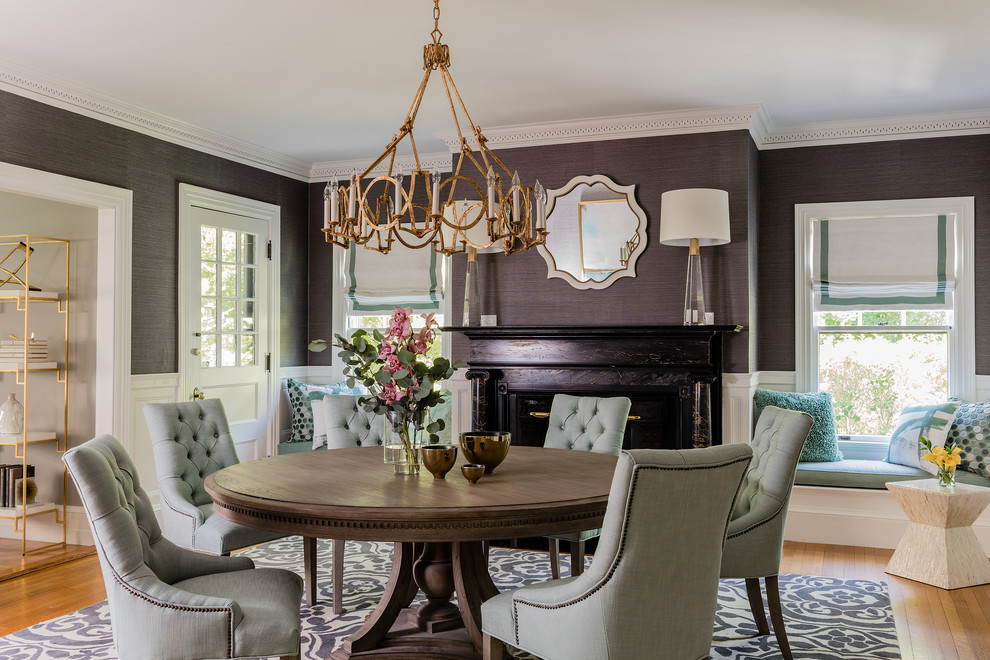 This is an example of a transitional dining room in Boston with grey walls, medium hardwood floors, a standard fireplace, a stone fireplace surround and brown floor.