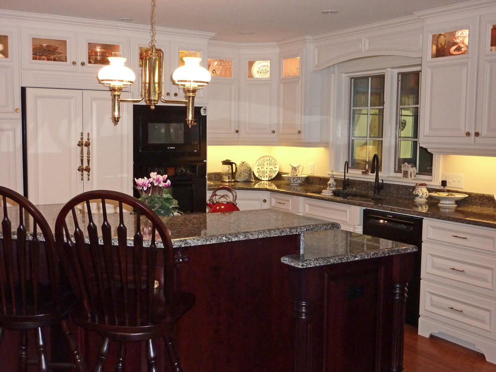 Inspiration for a mid-sized transitional l-shaped medium tone wood floor and brown floor open concept kitchen remodel with an undermount sink, raised-panel cabinets, white cabinets, granite countertops, black appliances, an island and gray countertops