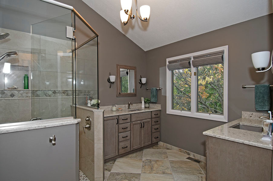 Photo of a large traditional master bathroom in Columbus with shaker cabinets, light wood cabinets, a corner shower, beige tile, ceramic tile, an undermount sink, quartzite benchtops, brown walls and ceramic floors.