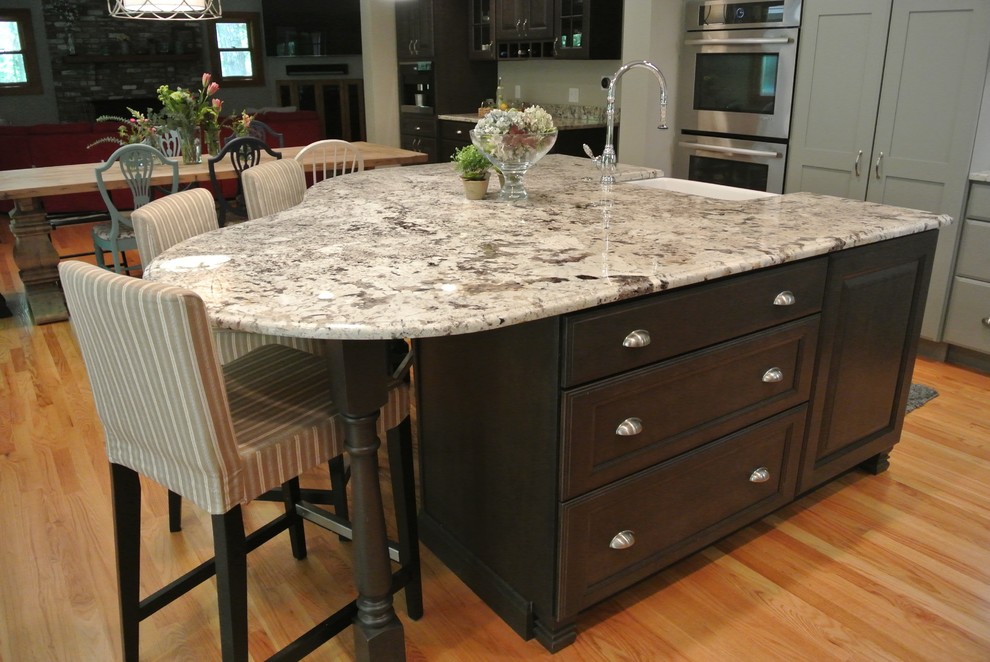 Large transitional l-shaped light wood floor eat-in kitchen photo in Boston with a farmhouse sink, shaker cabinets, gray cabinets, granite countertops, white backsplash, ceramic backsplash, stainless steel appliances, an island and gray countertops
