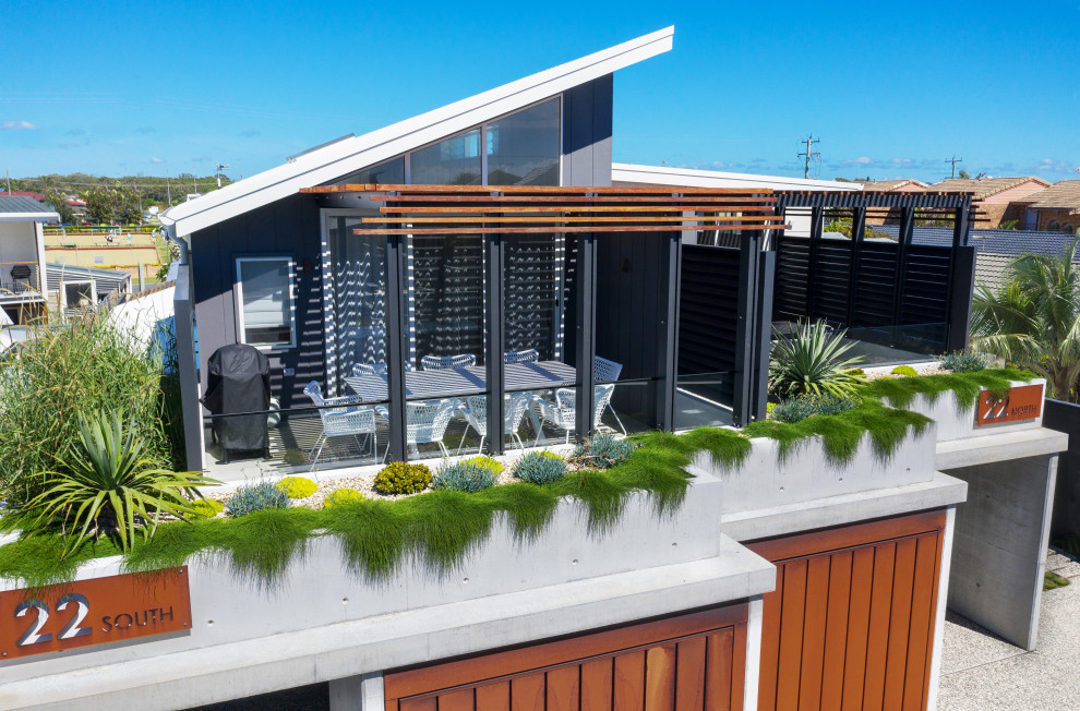 Example of a beach style white two-story concrete and board and batten duplex exterior design in Sydney with a metal roof and a white roof