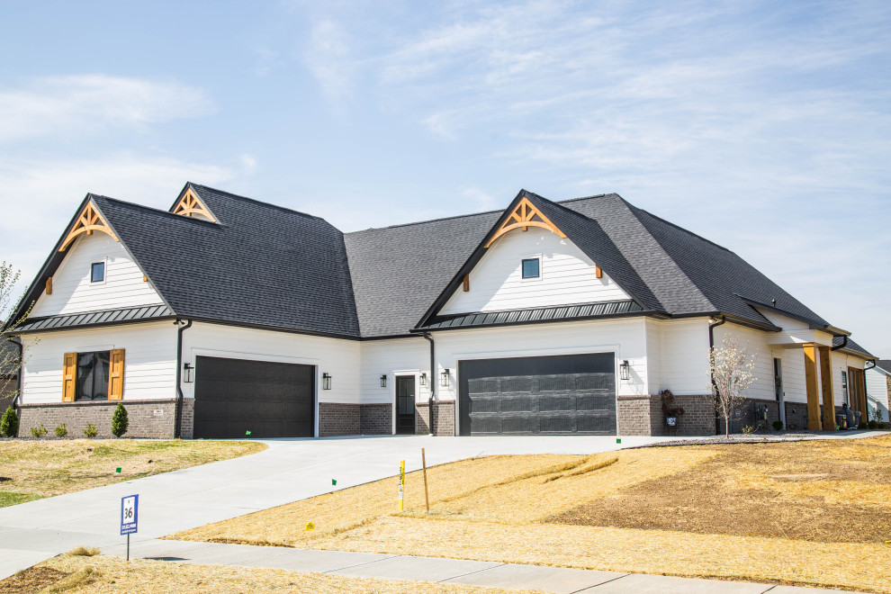 На фото: большой, одноэтажный, разноцветный частный загородный дом в стиле неоклассика (современная классика) с комбинированной облицовкой, двускатной крышей, крышей из смешанных материалов, черной крышей и отделкой планкеном