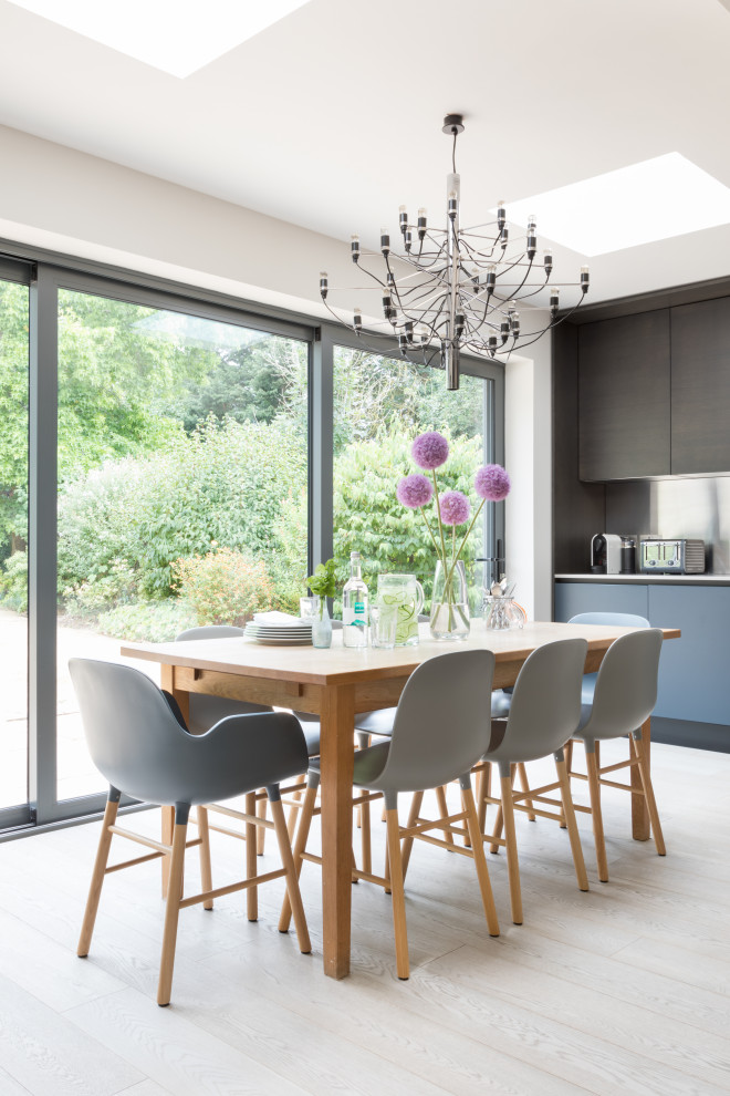 This is an example of a large contemporary eat-in kitchen in Sussex with a drop-in sink, flat-panel cabinets, dark wood cabinets, solid surface benchtops, metallic splashback, stainless steel appliances, medium hardwood floors, with island, grey floor and grey benchtop.