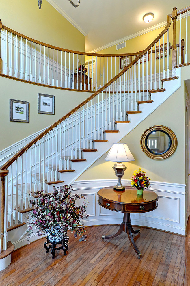 Traditional wood curved staircase in Philadelphia with painted wood risers.