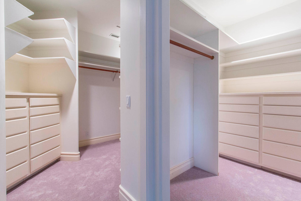 Large contemporary gender-neutral walk-in wardrobe in Los Angeles with flat-panel cabinets, white cabinets, carpet and pink floor.