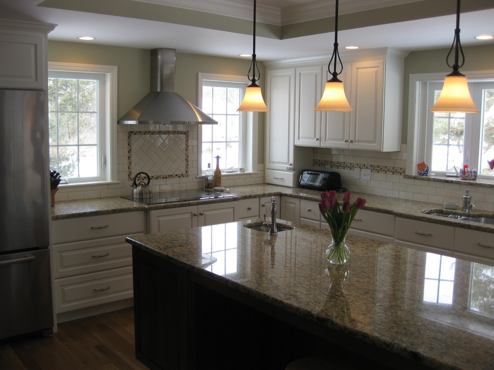 Inspiration for a transitional u-shaped medium tone wood floor eat-in kitchen remodel in Boston with an undermount sink, raised-panel cabinets, white cabinets, granite countertops, white backsplash, ceramic backsplash, stainless steel appliances, an island and beige countertops