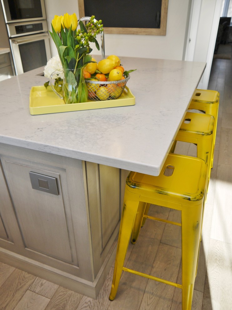Inspiration for a mid-sized transitional l-shaped light wood floor enclosed kitchen remodel in Toronto with an undermount sink, recessed-panel cabinets, gray cabinets, quartz countertops, white backsplash, porcelain backsplash, stainless steel appliances and an island