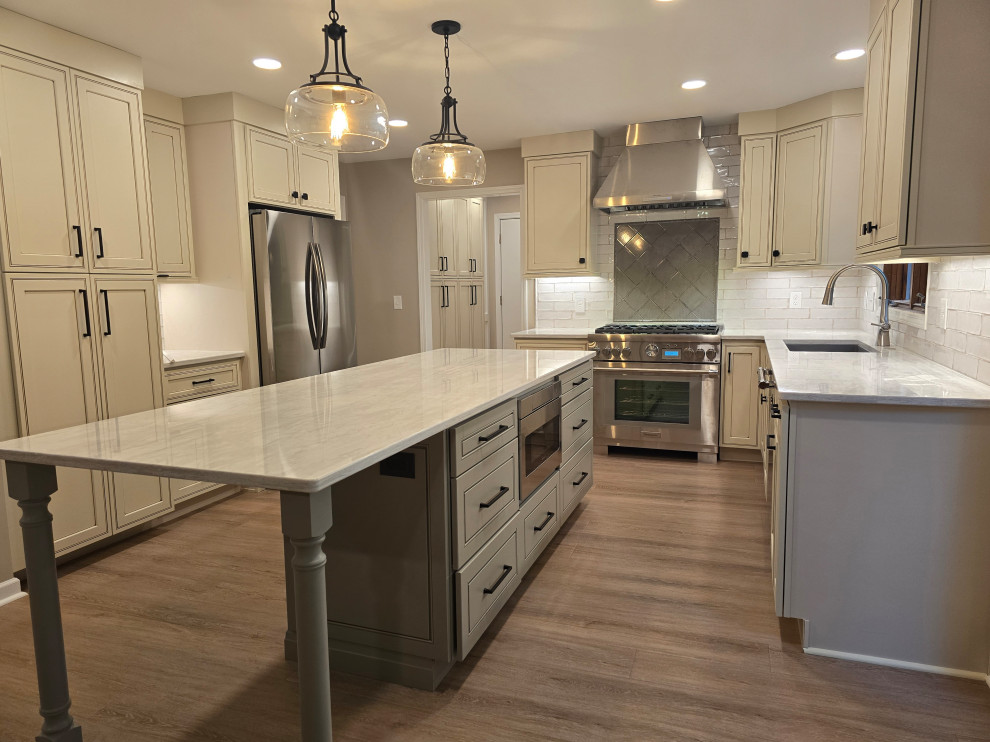 Enclosed kitchen - large modern medium tone wood floor and brown floor enclosed kitchen idea with an undermount sink, shaker cabinets, beige cabinets, quartz countertops, white backsplash, ceramic backsplash, stainless steel appliances, an island and black countertops