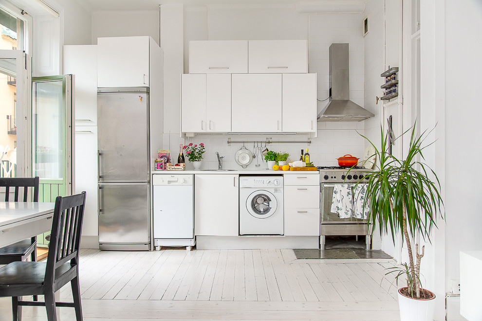 This is an example of a mid-sized scandinavian single-wall separate kitchen in Stockholm with flat-panel cabinets, white cabinets, laminate benchtops, ceramic splashback, white appliances, painted wood floors and no island.