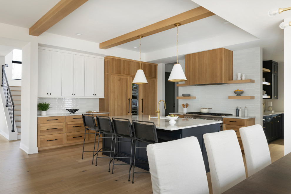 Moderne Küche mit Einbauwaschbecken, hellen Holzschränken, Quarzwerkstein-Arbeitsplatte, Küchengeräten aus Edelstahl, hellem Holzboden, Kücheninsel und gewölbter Decke in Minneapolis