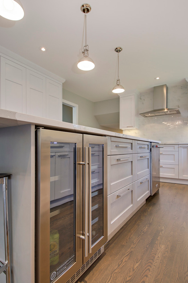 Eat-in kitchen - transitional l-shaped medium tone wood floor eat-in kitchen idea in Calgary with an undermount sink, shaker cabinets, white cabinets, quartz countertops, white backsplash, porcelain backsplash, stainless steel appliances and an island