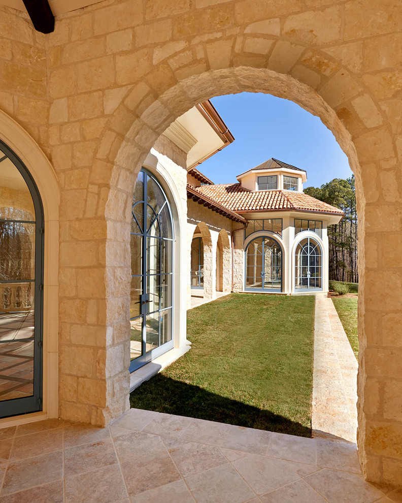 This is an example of an expansive traditional one-storey beige exterior in Raleigh with stone veneer.