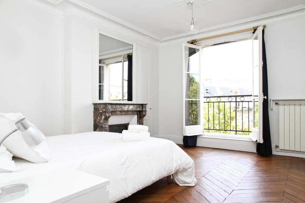 Esempio di una camera da letto tradizionale con pareti bianche, pavimento in legno massello medio, camino classico, cornice del camino in pietra e soffitto ribassato