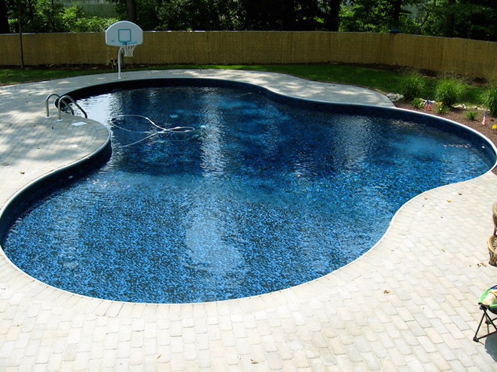 Mid-sized traditional backyard custom-shaped lap pool in Philadelphia with brick pavers.