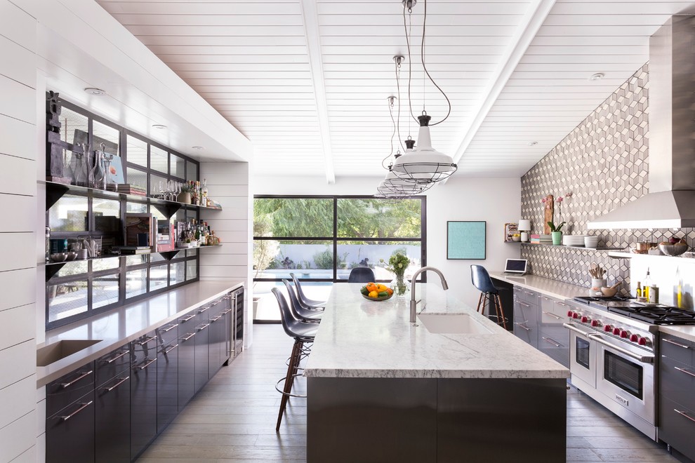 Inspiration for a midcentury galley kitchen in Los Angeles with an undermount sink, flat-panel cabinets, grey cabinets, multi-coloured splashback, stainless steel appliances, medium hardwood floors and with island.