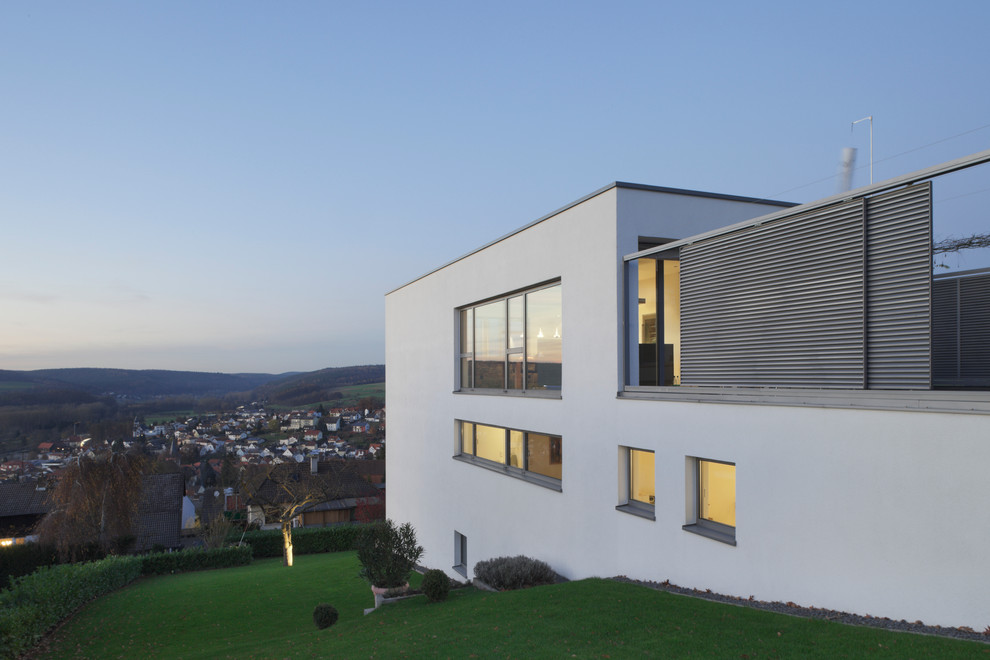 This is an example of a large contemporary three-storey white exterior in Frankfurt with a flat roof.