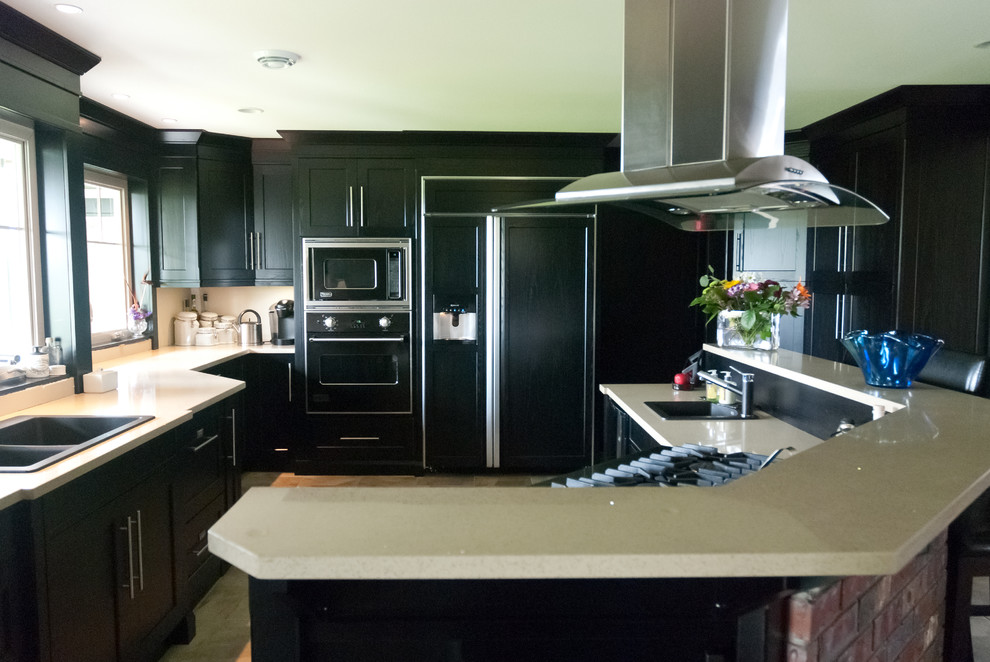 Photo of a contemporary l-shaped eat-in kitchen in Vancouver with a drop-in sink, shaker cabinets, black cabinets, quartz benchtops and panelled appliances.