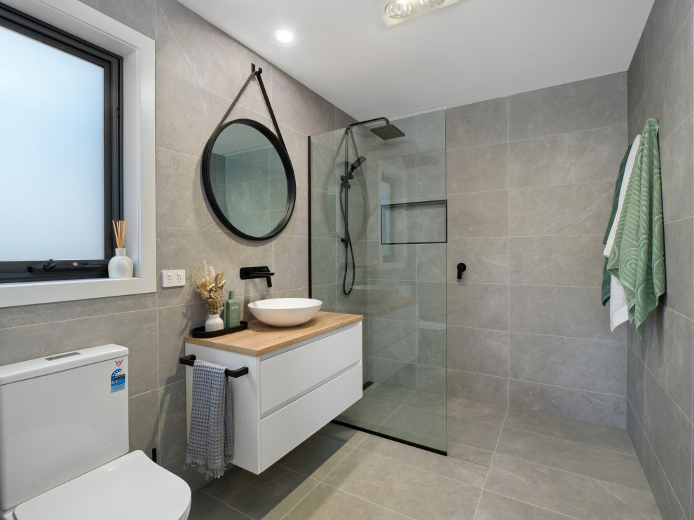 Bild på ett funkis badrum, med vita skåp, en öppen dusch, grå kakel, keramikplattor, klinkergolv i keramik, träbänkskiva och med dusch som är öppen