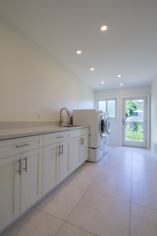 This is an example of a large contemporary single-wall utility room in Hawaii with an undermount sink, shaker cabinets, white cabinets, quartz benchtops, white walls, ceramic floors, a side-by-side washer and dryer and grey floor.