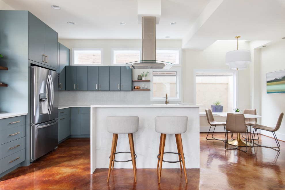 Inspiration for a mid-sized transitional l-shaped open plan kitchen in Austin with an undermount sink, flat-panel cabinets, green cabinets, quartz benchtops, white splashback, mosaic tile splashback, stainless steel appliances, concrete floors, with island, brown floor and white benchtop.