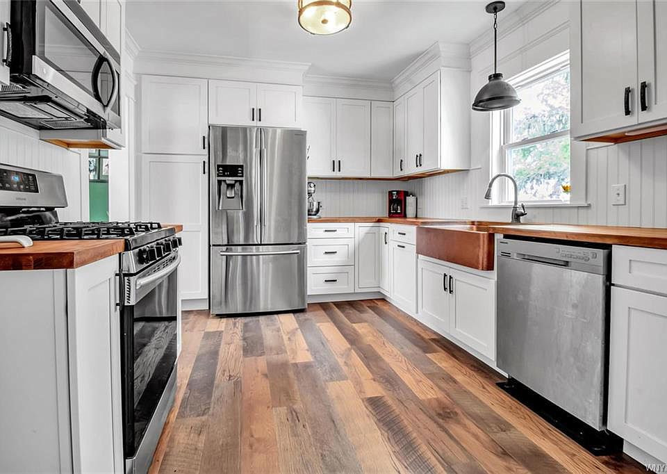 Design ideas for a small country u-shaped separate kitchen in Other with a farmhouse sink, shaker cabinets, white cabinets, wood benchtops, white splashback, shiplap splashback, stainless steel appliances, medium hardwood floors, no island, brown floor and brown benchtop.