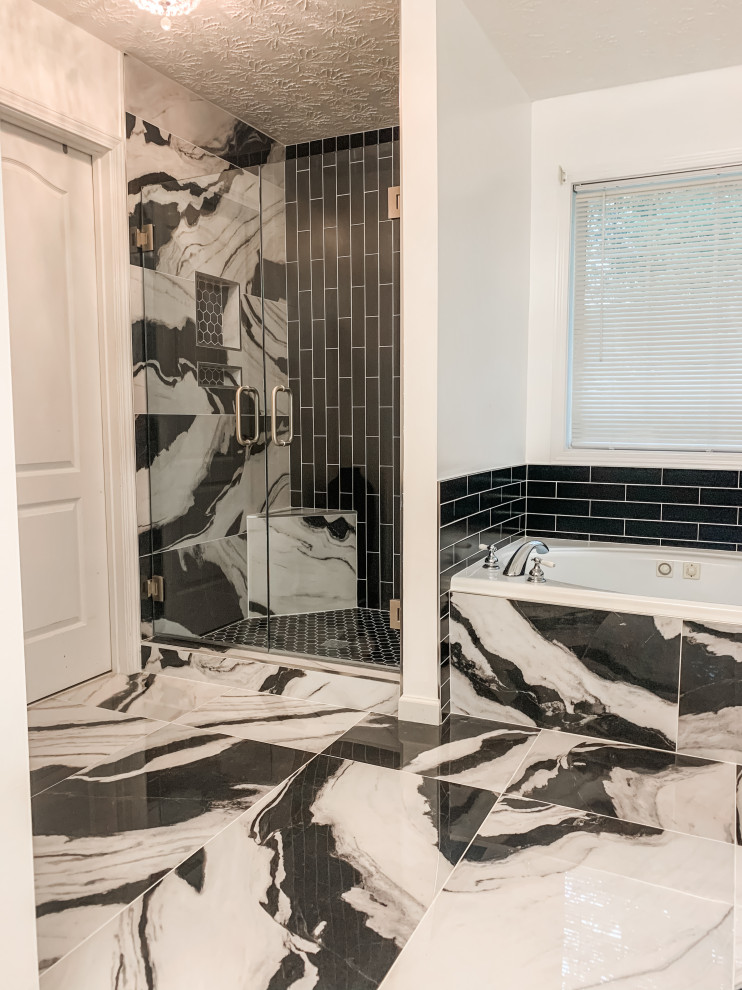 This is an example of a mid-sized contemporary master bathroom in Atlanta with glass-front cabinets, black cabinets, a claw-foot tub, an open shower, a one-piece toilet, black and white tile, marble, white walls, ceramic floors, a wall-mount sink, tile benchtops, black floor, an open shower, white benchtops, a niche, a double vanity, a built-in vanity, coffered and planked wall panelling.