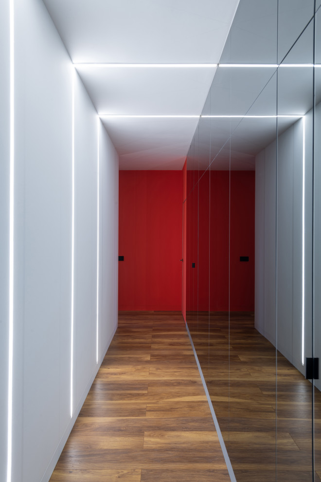 На фото: узкий коридор среднего размера в современном стиле с белыми стенами, полом из ламината, коричневым полом и обоями на стенах с