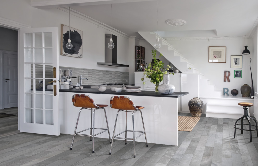 Small eclectic kitchen in Denver with flat-panel cabinets, white cabinets, porcelain splashback, stainless steel appliances, porcelain floors, a peninsula and grey floor.