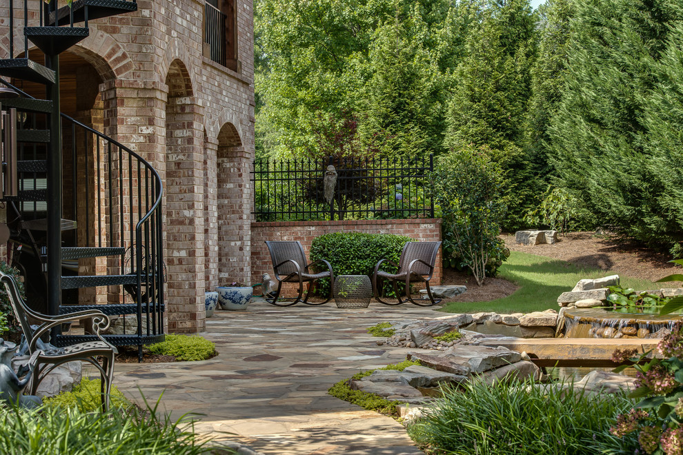 This is an example of a large transitional backyard patio in Atlanta with natural stone pavers and no cover.