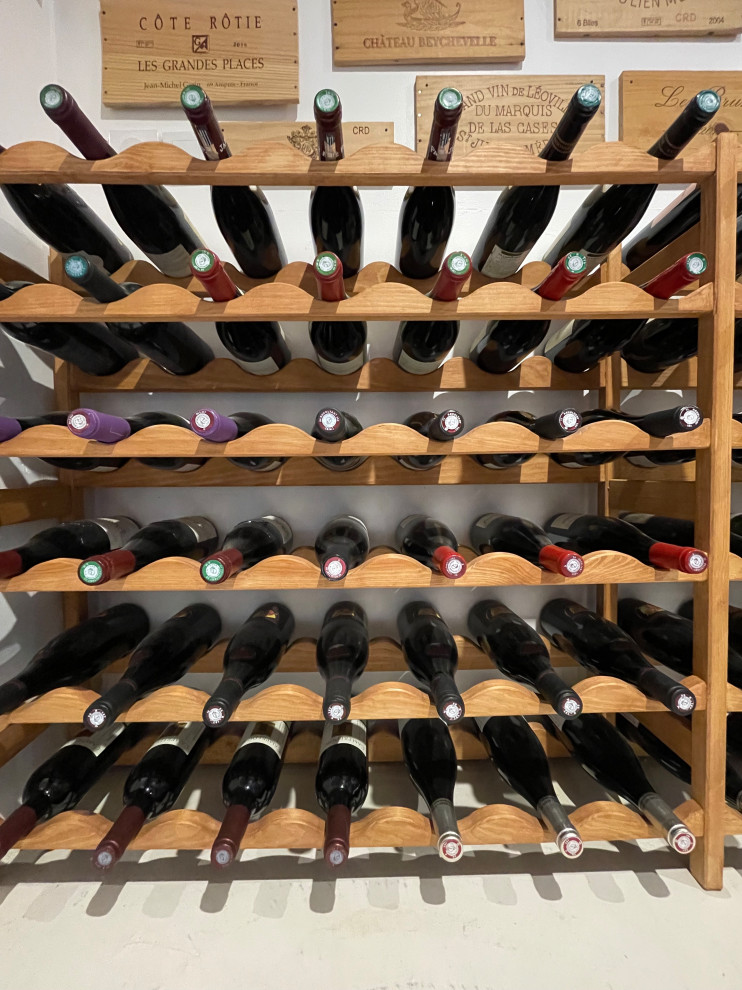 Photo of a mid-sized modern wine cellar in Grenoble with concrete floors, display racks and white floor.