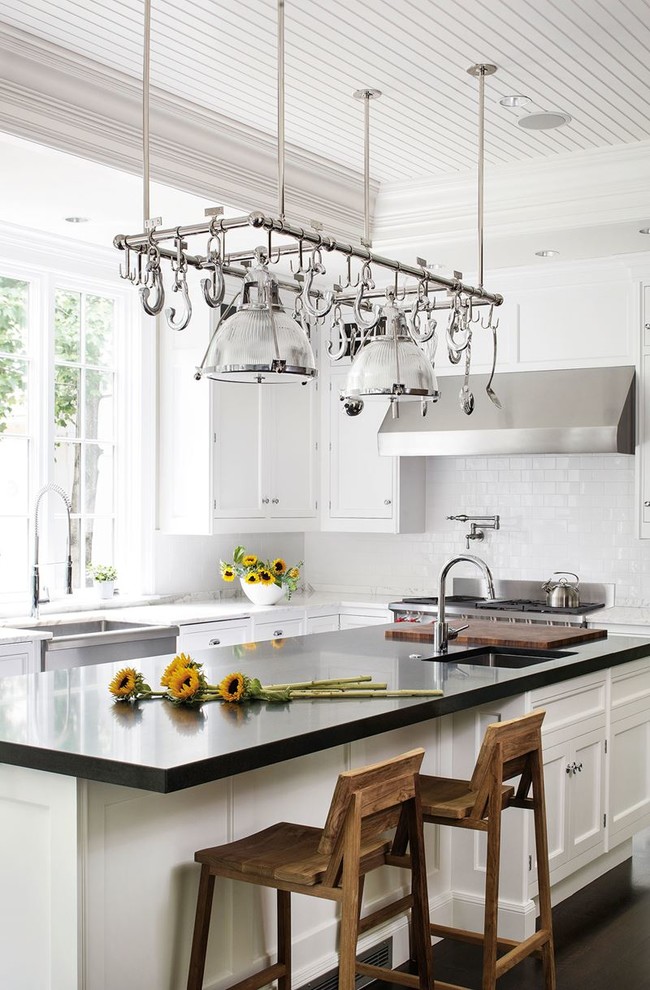 Inspiration for a traditional l-shaped kitchen in New York with a farmhouse sink, shaker cabinets, white cabinets, white splashback, subway tile splashback, stainless steel appliances, dark hardwood floors and with island.