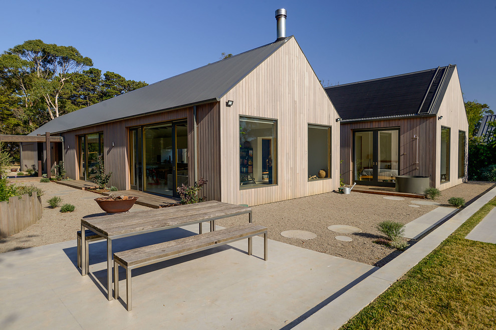 Large contemporary one-storey brown house exterior in Melbourne with wood siding, a gable roof and a metal roof.
