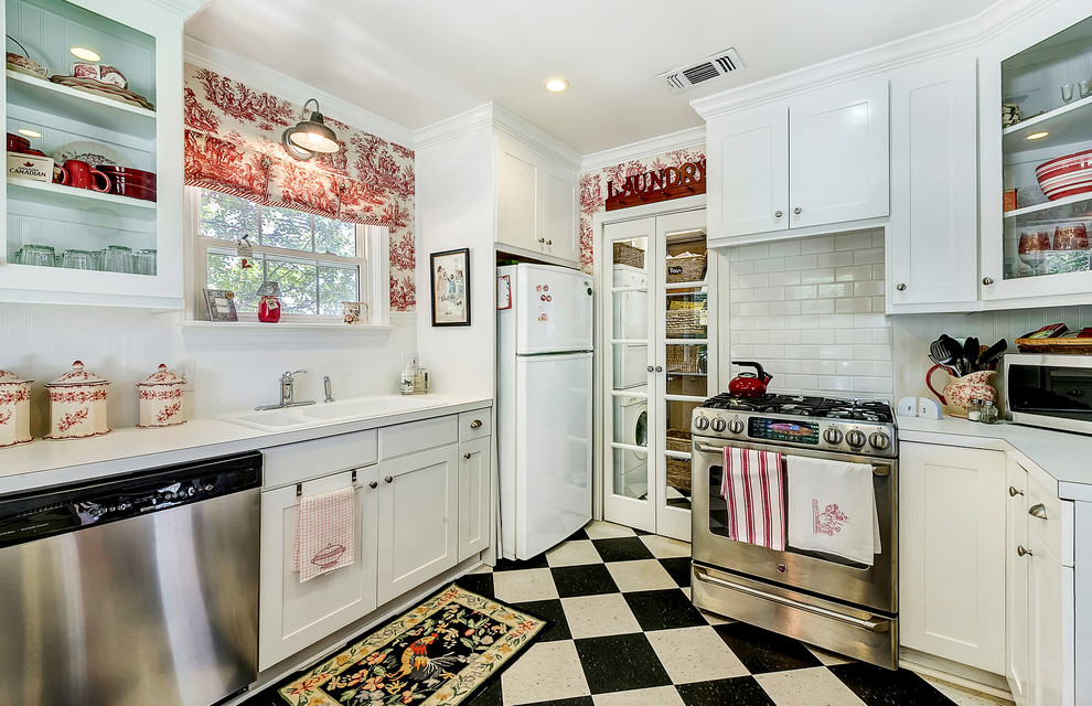 This is an example of a small traditional kitchen in Dallas with a double-bowl sink, shaker cabinets, white cabinets, white splashback, subway tile splashback and stainless steel appliances.