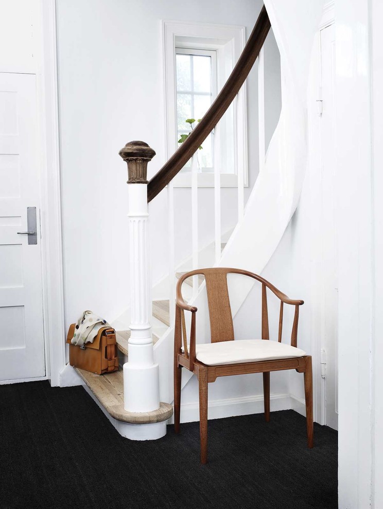 This is an example of a transitional entryway in New York with white walls and black floor.