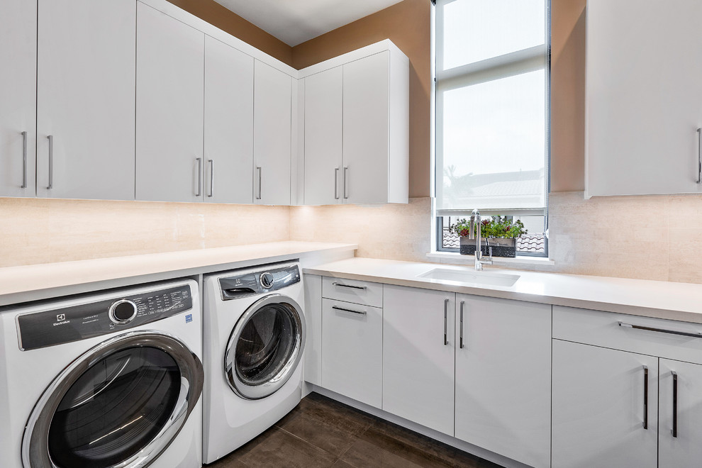 Design ideas for a large modern dedicated laundry room in Miami with an undermount sink, flat-panel cabinets, white cabinets, white walls, medium hardwood floors, a side-by-side washer and dryer, brown floor and white benchtop.