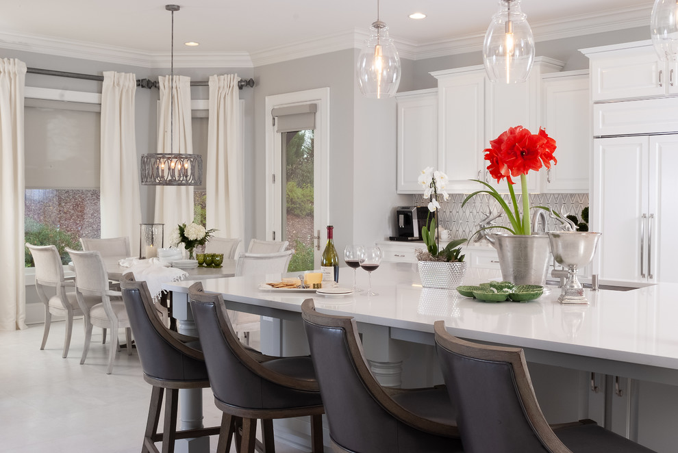 Expansive traditional l-shaped eat-in kitchen in Atlanta with an undermount sink, raised-panel cabinets, white cabinets, solid surface benchtops, grey splashback, marble splashback, stainless steel appliances, with island, white floor and white benchtop.