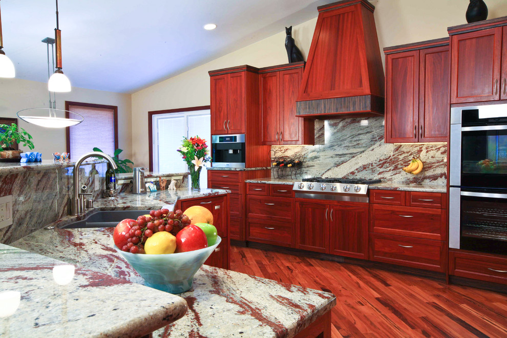 Open concept kitchen - mid-sized transitional l-shaped medium tone wood floor and brown floor open concept kitchen idea in Seattle with an undermount sink, recessed-panel cabinets, medium tone wood cabinets, granite countertops, gray backsplash, stone slab backsplash, stainless steel appliances and an island