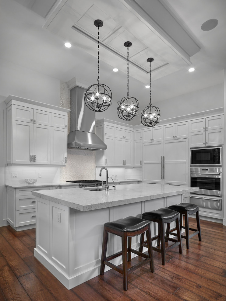 Large arts and crafts u-shaped medium tone wood floor and brown floor eat-in kitchen photo with an undermount sink, shaker cabinets, white cabinets, quartz countertops, white backsplash, subway tile backsplash, stainless steel appliances and an island