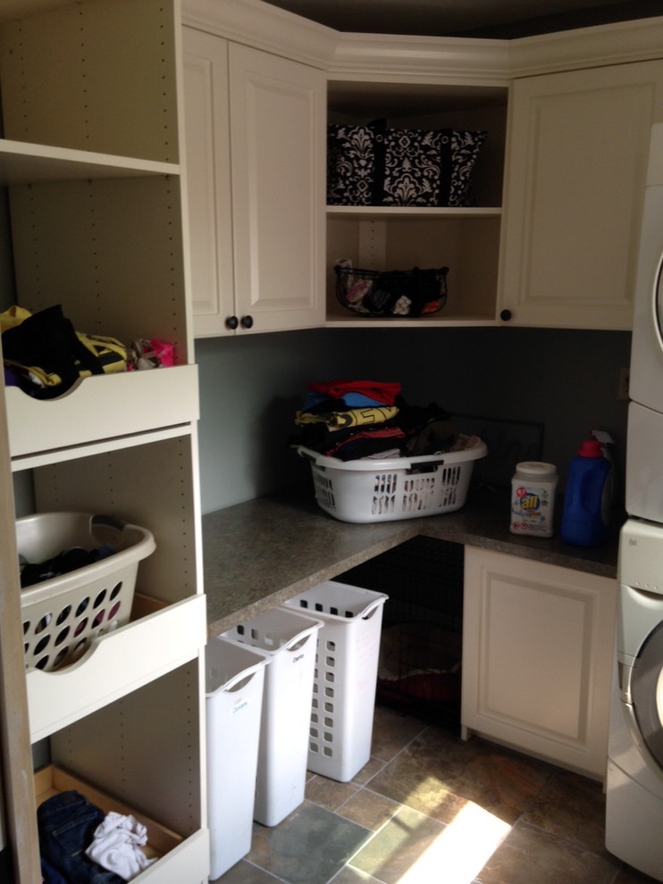 Inspiration for a mid-sized transitional l-shaped dedicated laundry room in Cleveland with raised-panel cabinets, white cabinets, laminate benchtops, grey walls, linoleum floors and a stacked washer and dryer.