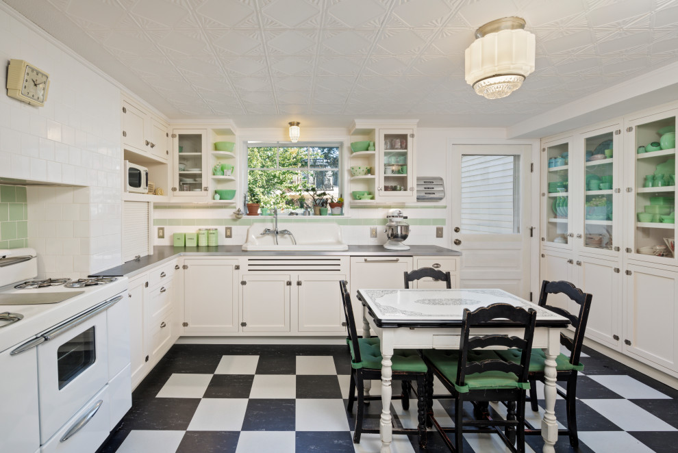 Inspiration for a mid-sized victorian u-shaped linoleum floor and multicolored floor enclosed kitchen remodel in New York with shaker cabinets, white cabinets, laminate countertops, white backsplash, white appliances, no island and black countertops