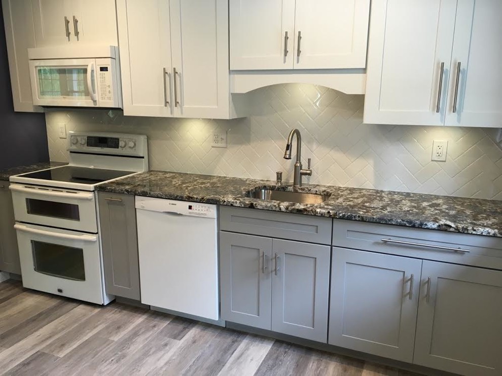 Example of a mid-sized transitional single-wall vinyl floor eat-in kitchen design in New York with an undermount sink, shaker cabinets, white cabinets, granite countertops, white backsplash, subway tile backsplash, white appliances and an island