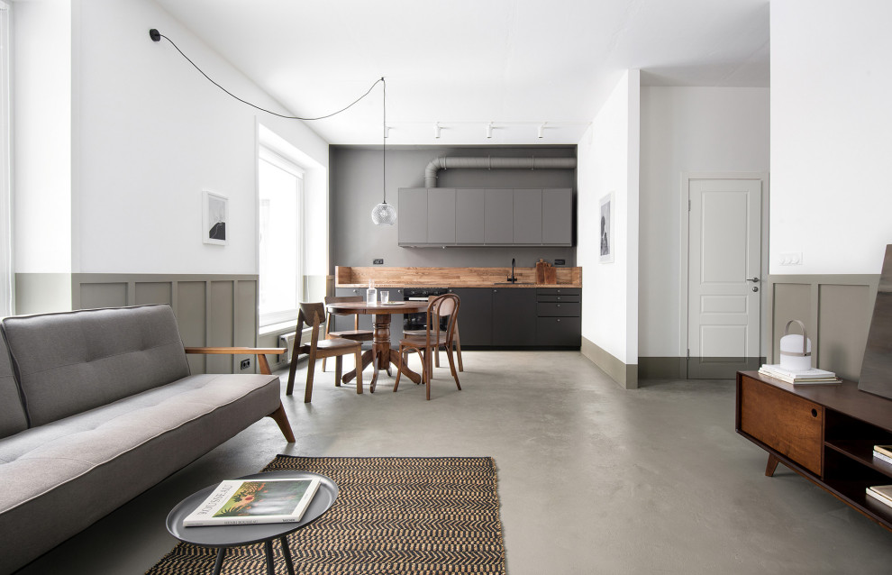 Idéer för att renovera ett mellanstort funkis brun linjärt brunt kök med öppen planlösning, med en nedsänkt diskho, släta luckor, svarta skåp, träbänkskiva, brunt stänkskydd, stänkskydd i trä, svarta vitvaror, betonggolv och grått golv