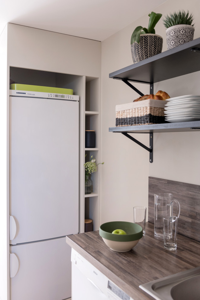 Idée de décoration pour une cuisine ouverte design de taille moyenne avec un évier 1 bac, un plan de travail en bois et une crédence grise.