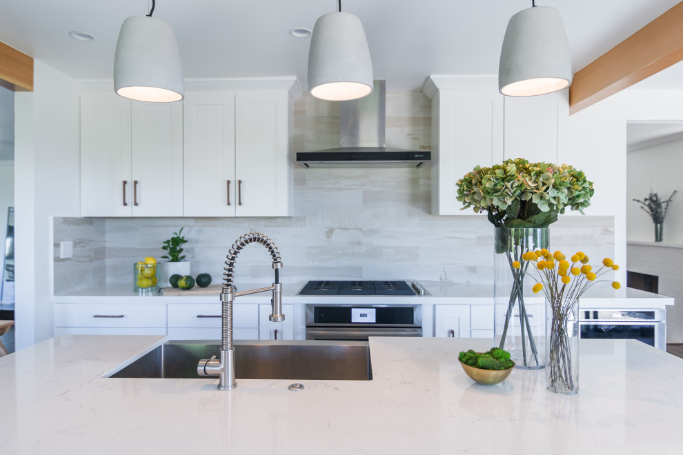Mid-sized contemporary eat-in kitchen in Los Angeles with a single-bowl sink, shaker cabinets, white cabinets, quartz benchtops, beige splashback, porcelain splashback, stainless steel appliances, porcelain floors, with island, beige floor and white benchtop.