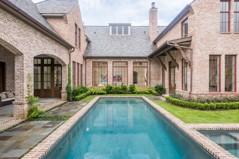 Design ideas for a mid-sized traditional courtyard rectangular pool in Houston with brick pavers and a hot tub.